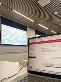 In a classroom at York University, a laptop is placed on a table in front of a projector screen, using the Moodle software.