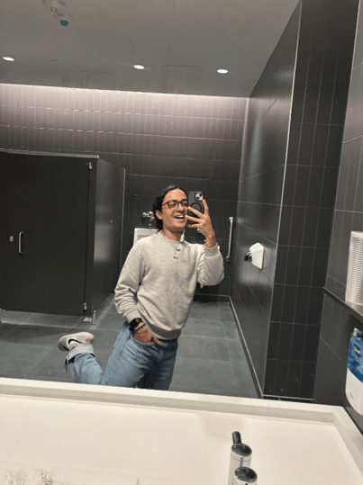 Boy smiling while taking a mirror selfie in the washroom.