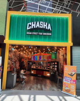 Picture shown an Indian street  style eating place named Chaska, a boy sitting on a chair and lights on the ceiling. 