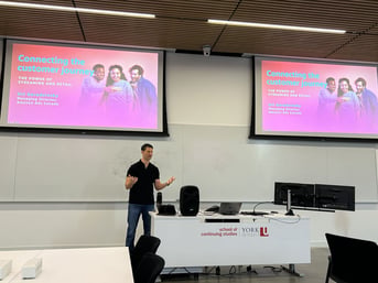 Man presenting in the a York SCS classroom with two projector screen in the background
