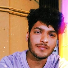 Selfie of rishabh kothari slightly smiling with light leak effect on the right side of the frame and a grainy filter on top of the image